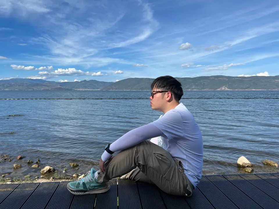 Jinhao sitting on a pier looking across Erhai Lake