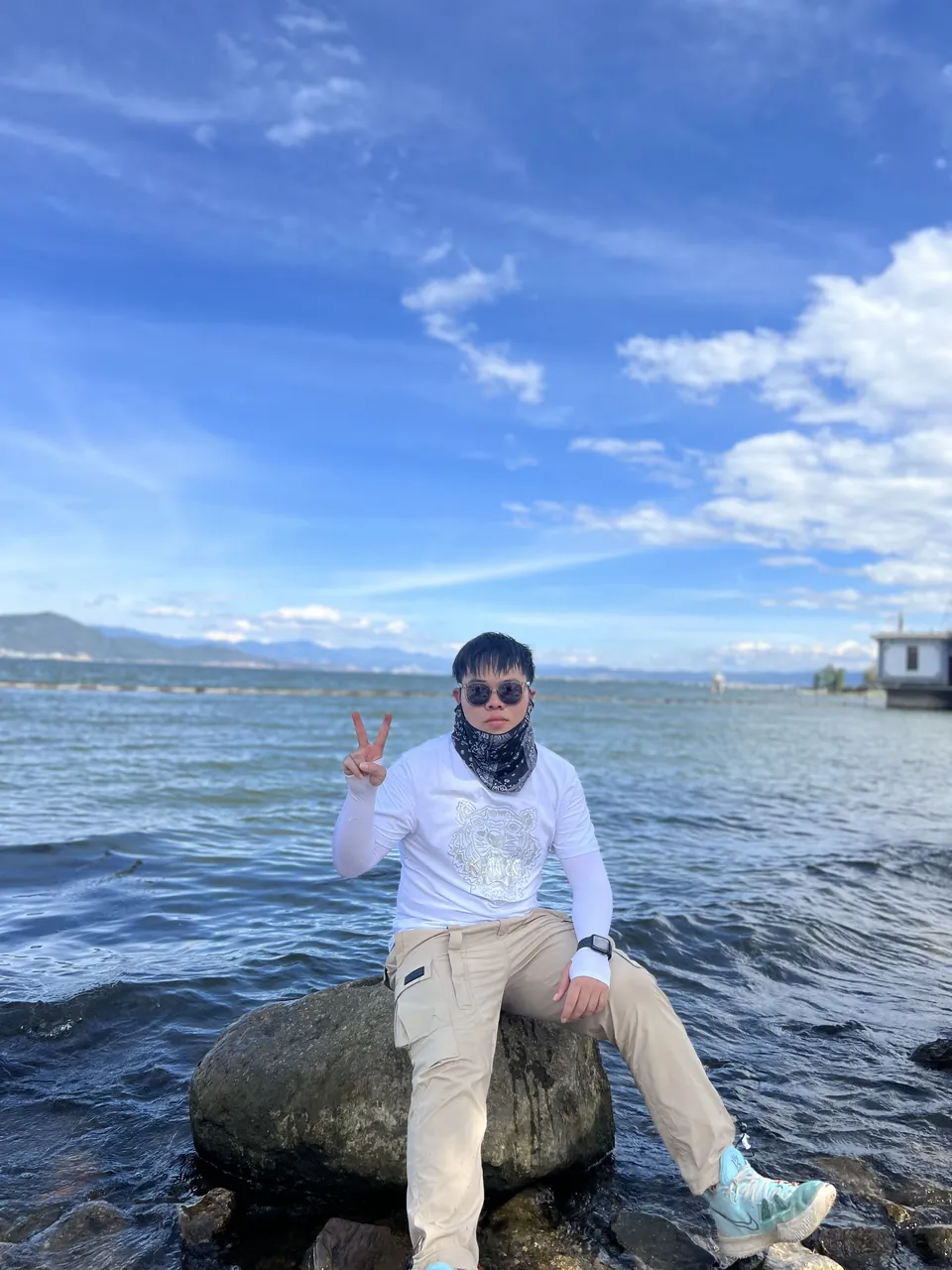 Jinhao sitting on a rock in Erhai Lake under a big blue sky