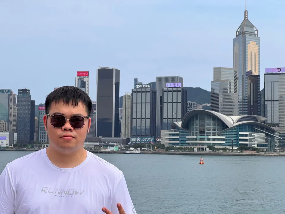 Jinhao in sunglasses in front of the Hong Kong skyline