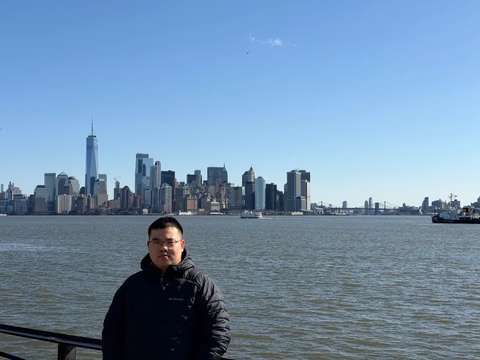 Jinhao by the water with the Lower Manhattan skyline across the harbor