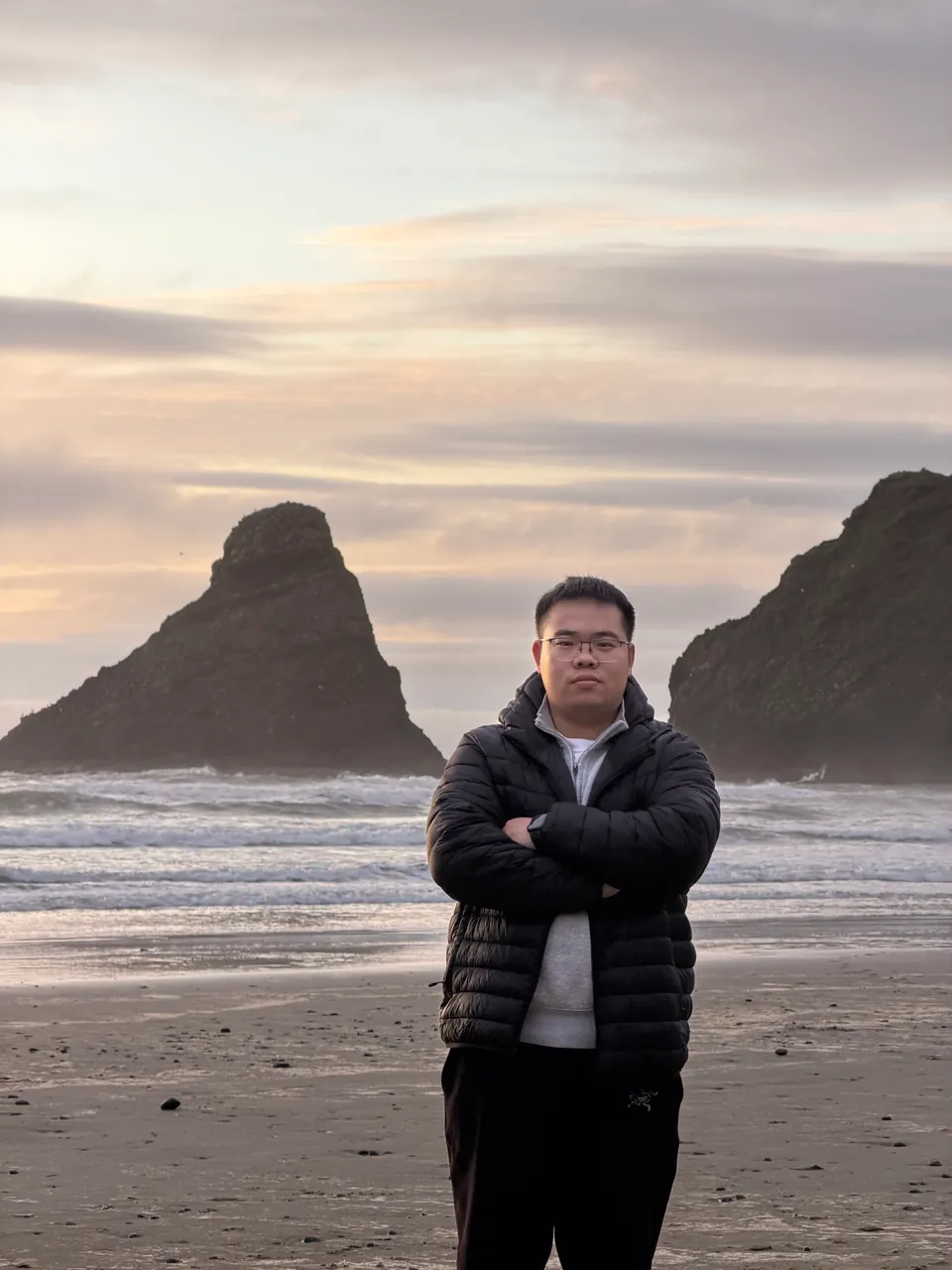 Jinhao on a beach between two dark sea stacks at dusk