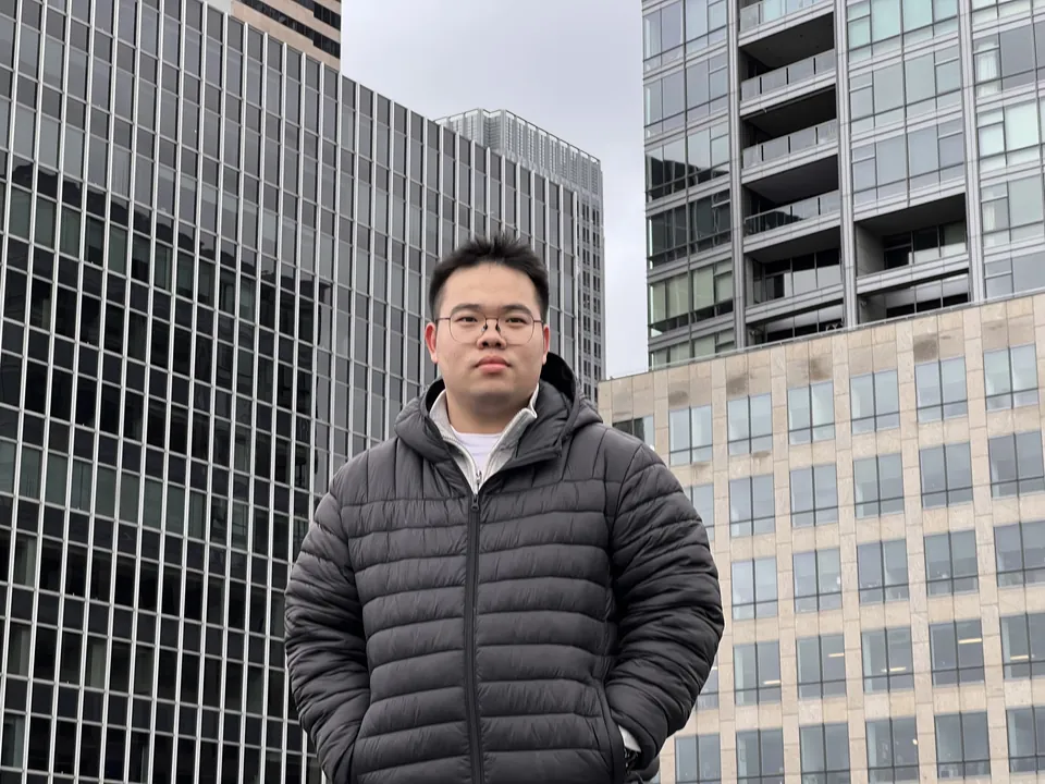 Jinhao in a puffer jacket between downtown Seattle towers