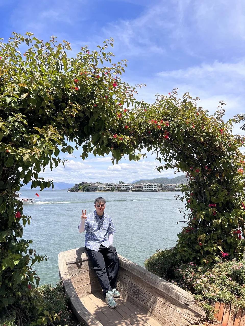 Jinhao under an arch of flowers by the lake