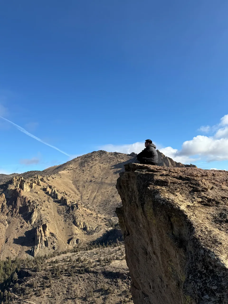 A lone figure on a rock spire under a blue sky