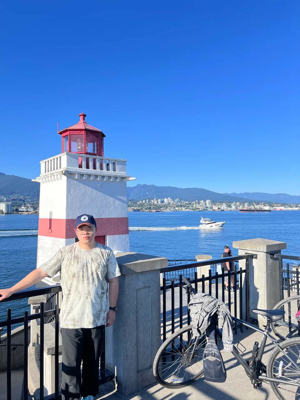 Jinhao by a red and white lighthouse on the seawall, the harbour behind