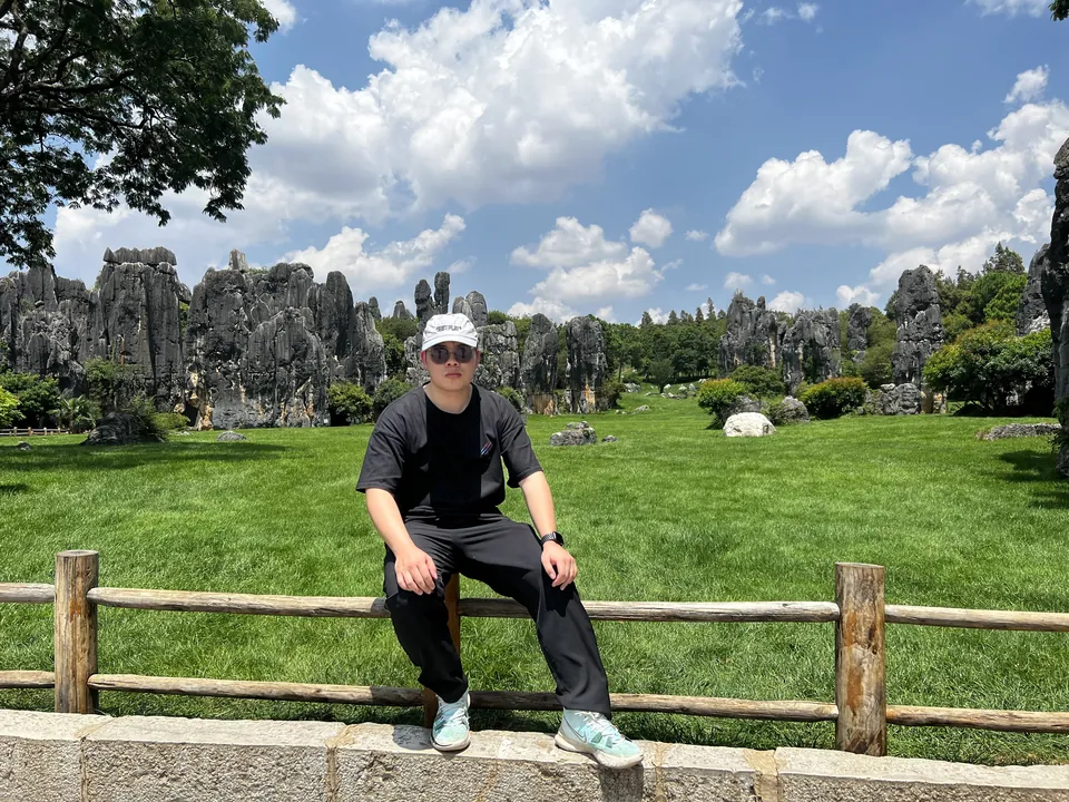 Jinhao sitting on a fence in front of grey limestone pillars