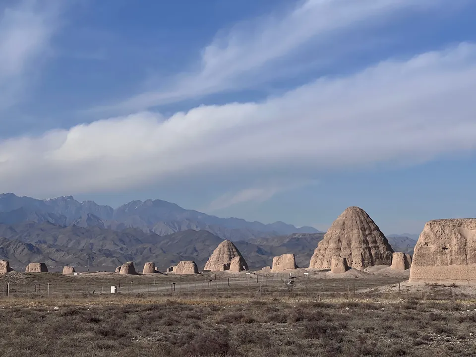 Ancient earthen tombs on a plain under long clouds