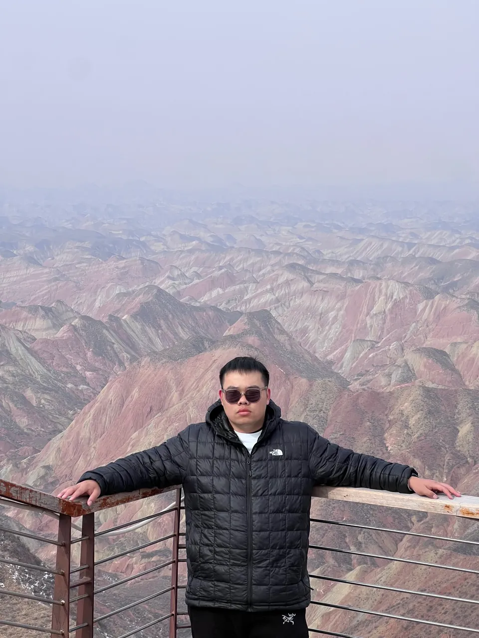 Jinhao on a viewing deck above striped rainbow mountains